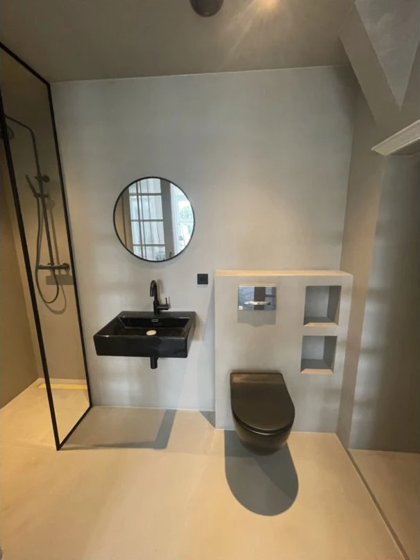 Een afgewerkte badkamer met ingebouwde nis, spiegel en zorgvuldig aangesloten oppervlakken.