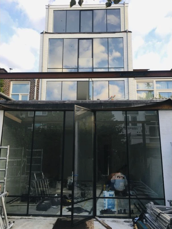 Gevel met grote glaspartijen en een extra bouwlaag, gefotografeerd vanaf buiten